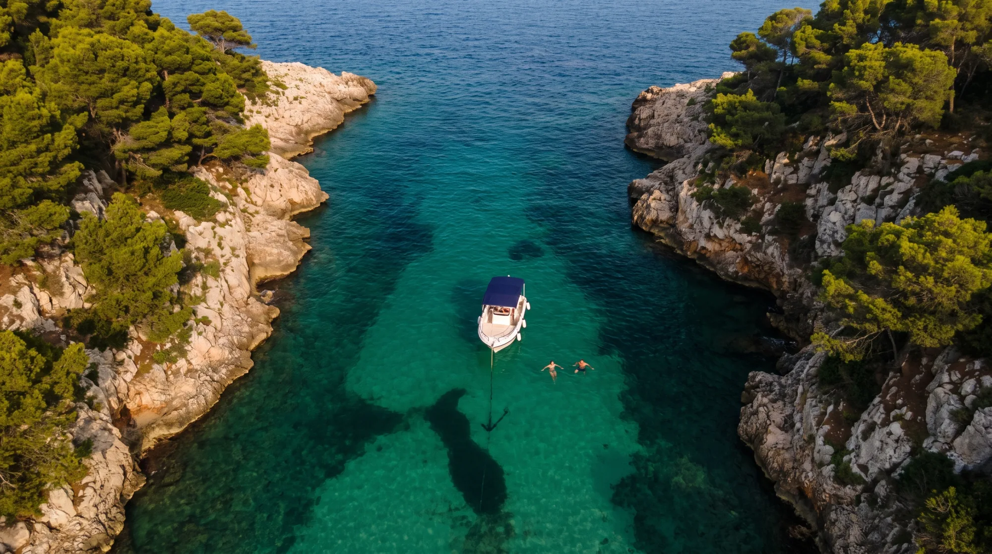 A single day boat at anchor in a narrow turquoise cove.